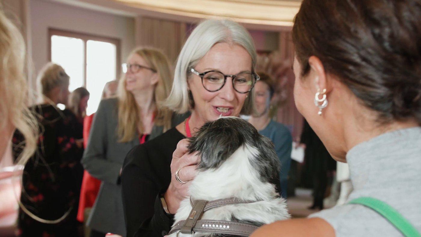A colleague making a fuss of a small dog at a company gathering
