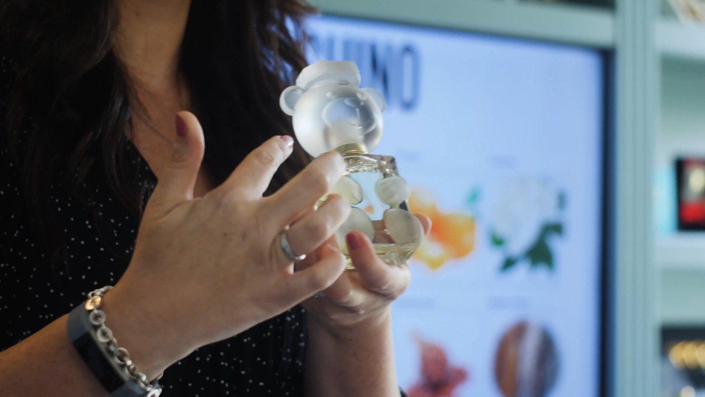 A hand turning a Moschino Toy bottle to the light during a training session