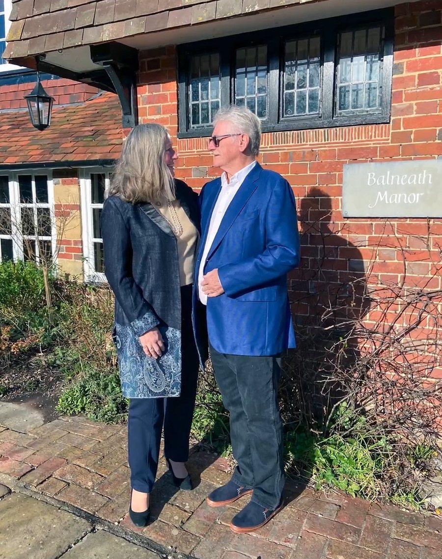 A couple standing outside the brick front of the manor