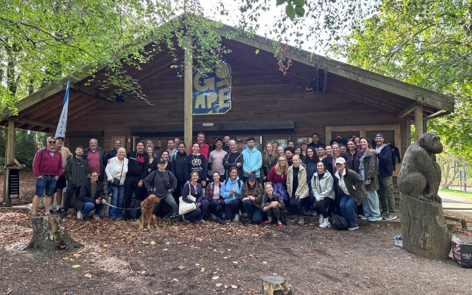 The whole team gathered for a photograph outside a timber lodge