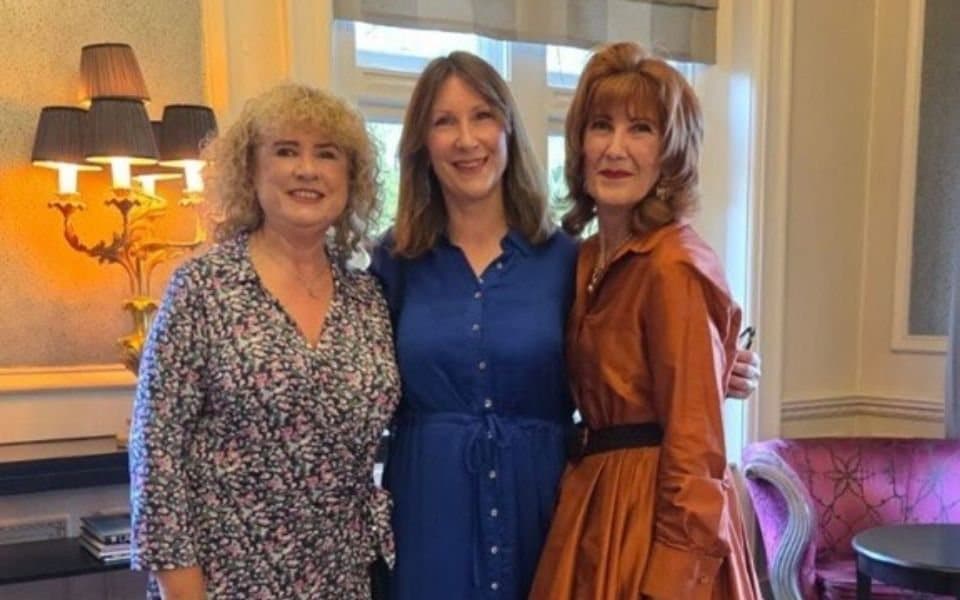 Three colleagues smiling together at an awards evening