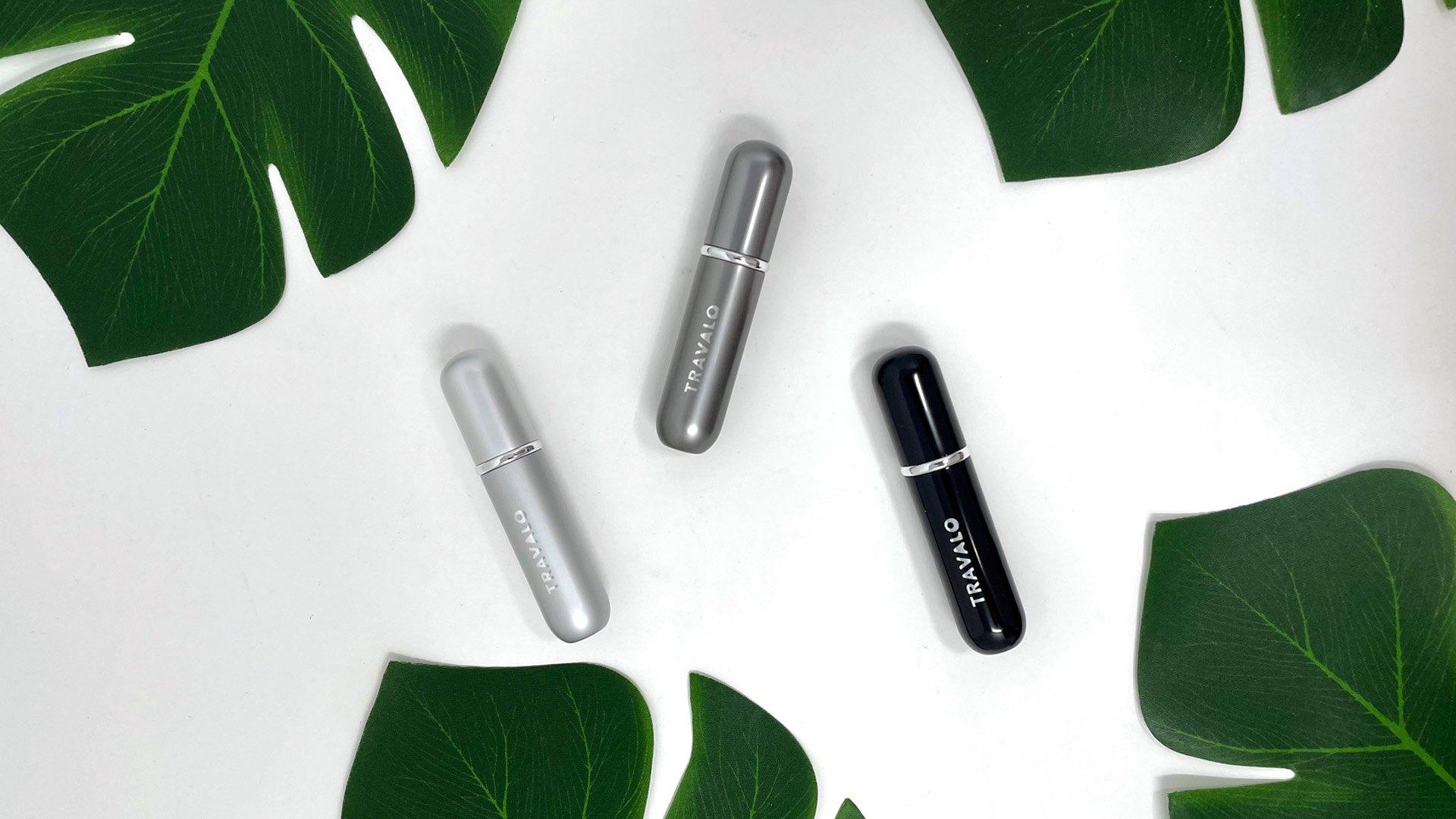 Three Travalo refillable atomisers between monstera leaves